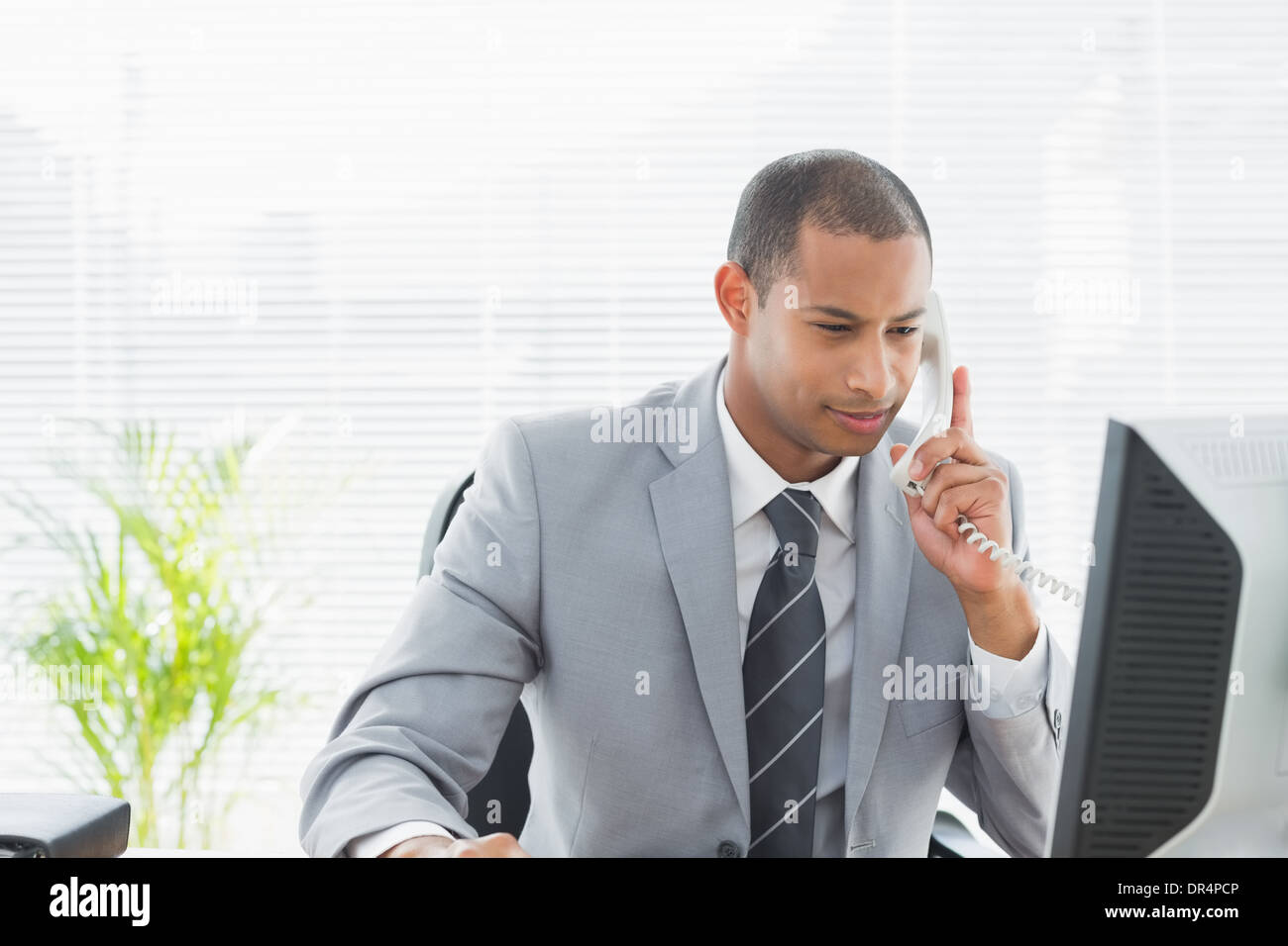 Businessman using computer and phone at office Stock Photo