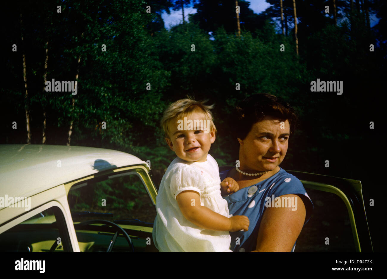 A mother holds her 2 year-old son among heather in country field during summer time in the early 1960s. Stock Photo