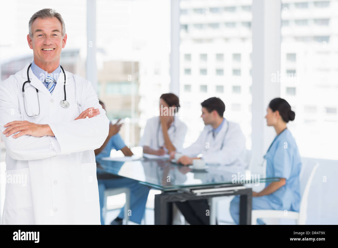 Doctor with group around table in background at hospital Stock Photo ...