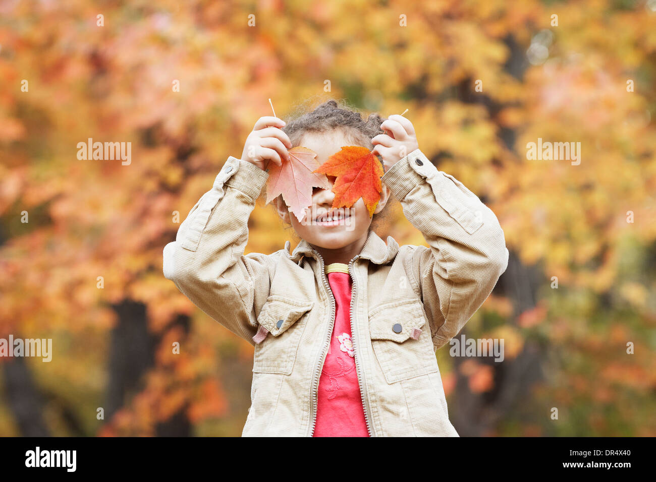 Hispanic girl holding autumn leaves over her eyes Stock Photo