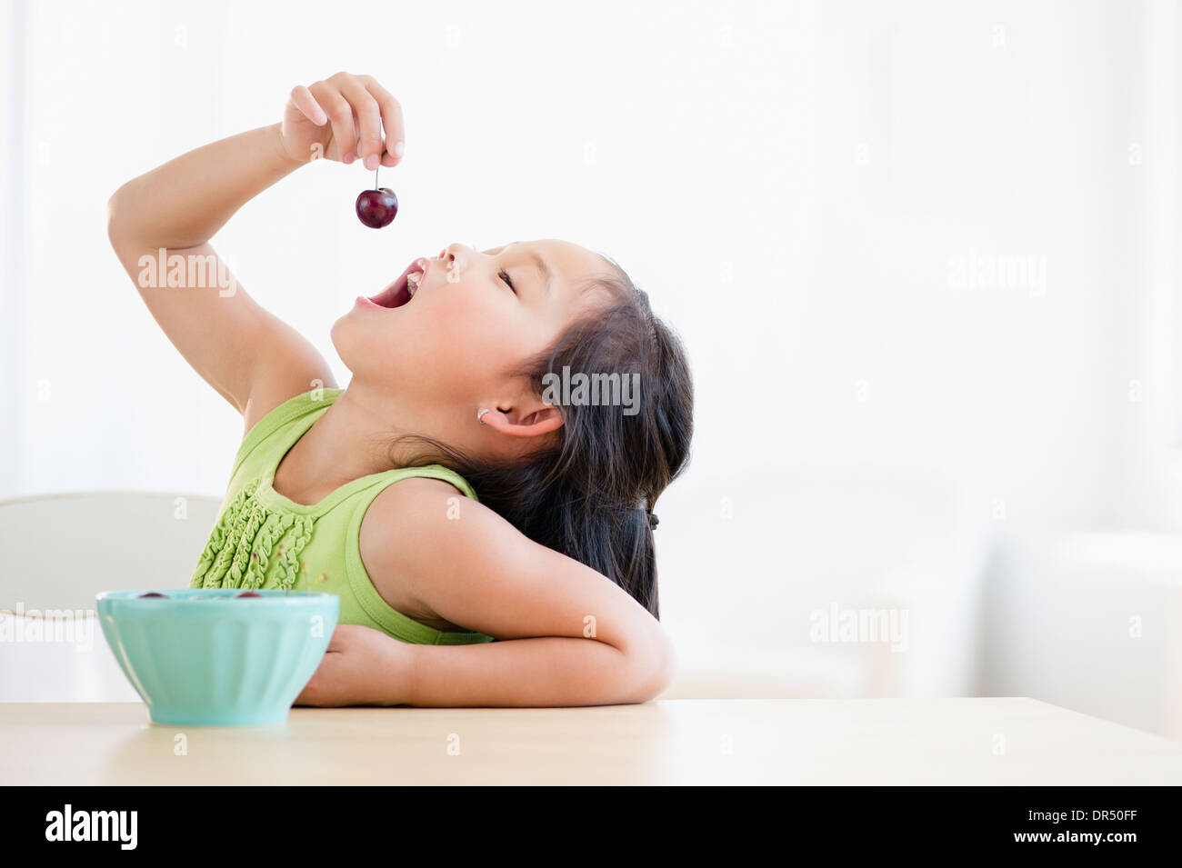 Korean girl eating bowl of fruit Stock Photo