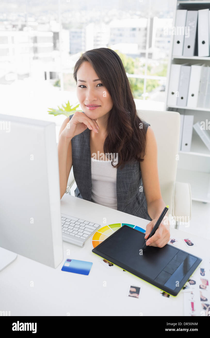 Smiling casual female photo editor using graphics tablet Stock Photo