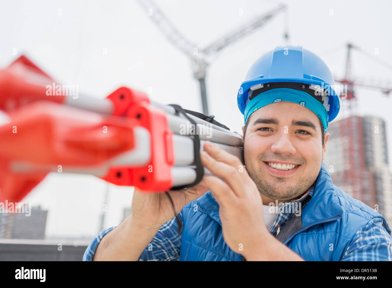Mixed race worker carrying metal on construction site Stock Photo