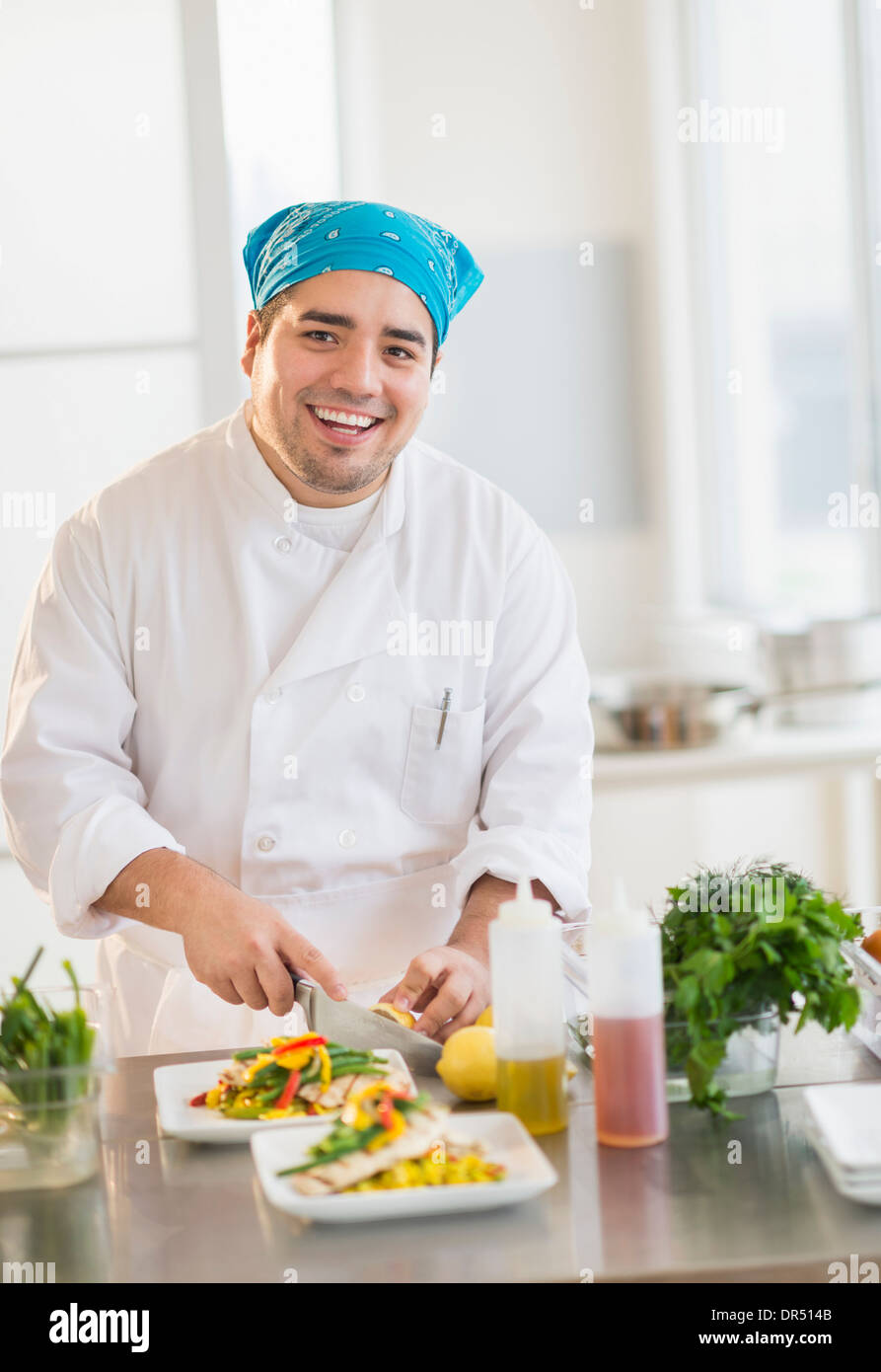 Mixed race chef plating food in restaurant Stock Photo