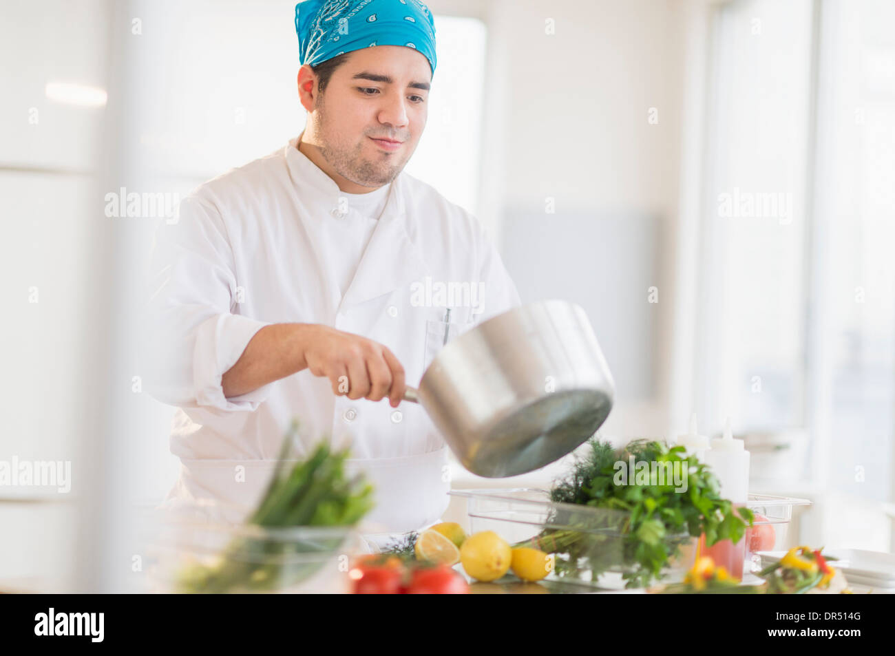 Mixed race chef cooking in restaurant Stock Photo