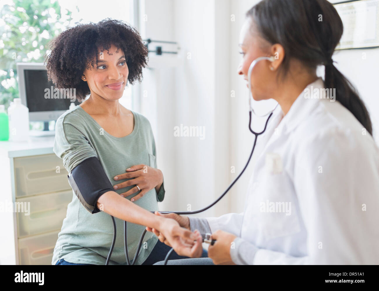 African American doctor taking pregnant woman's blood pressure Stock Photo