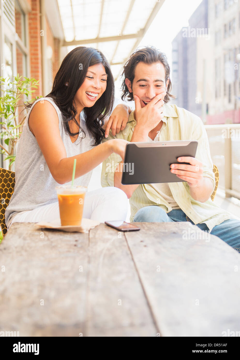 Couple using digital tablet at sidewalk cafe Stock Photo