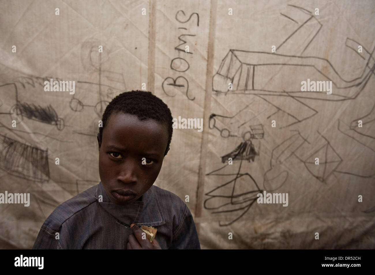 Dec 25, 2008 - Goma, Demoratic Republic of Congo - A displaced Congolese child stands in front of a drawing of airplanes bombing a village, on the side of a tent in the Kibati IDP (internally displaced person) camp on Christmas day, Thursday, December 25, 2008. (Credit Image: © T.J. Kirkpatrick/ZUMA Press) Stock Photo