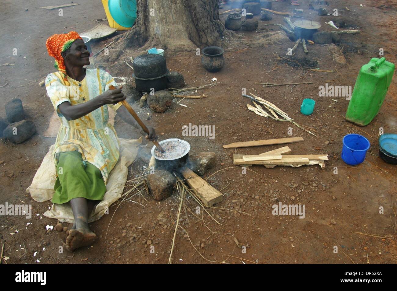 Old woman is cooking in a refugee camp in Uganda. Civil war has resulted in hundred of thousands of displaced people Stock Photo