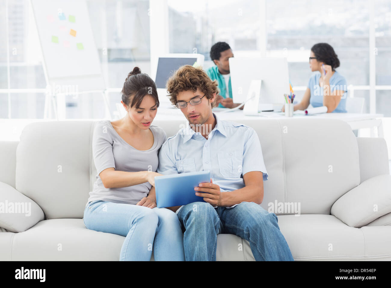 Couple using digital tablet with colleagues at creative office Stock Photo