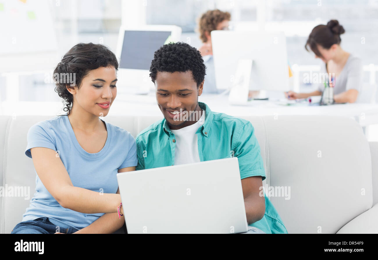 Couple using laptop with colleagues at creative office Stock Photo