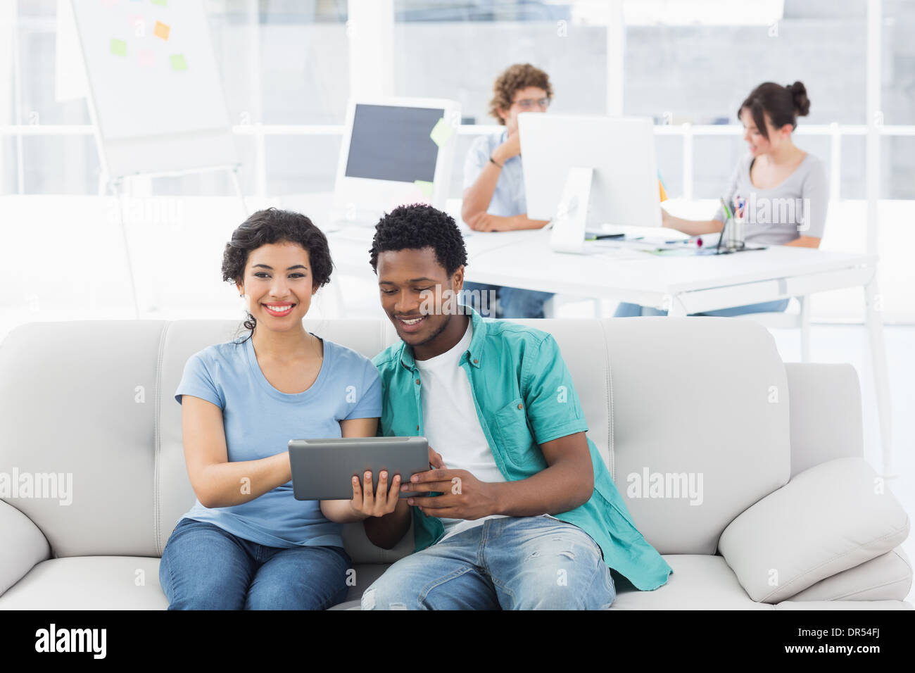 Couple using digital tablet with colleagues at creative office Stock Photo