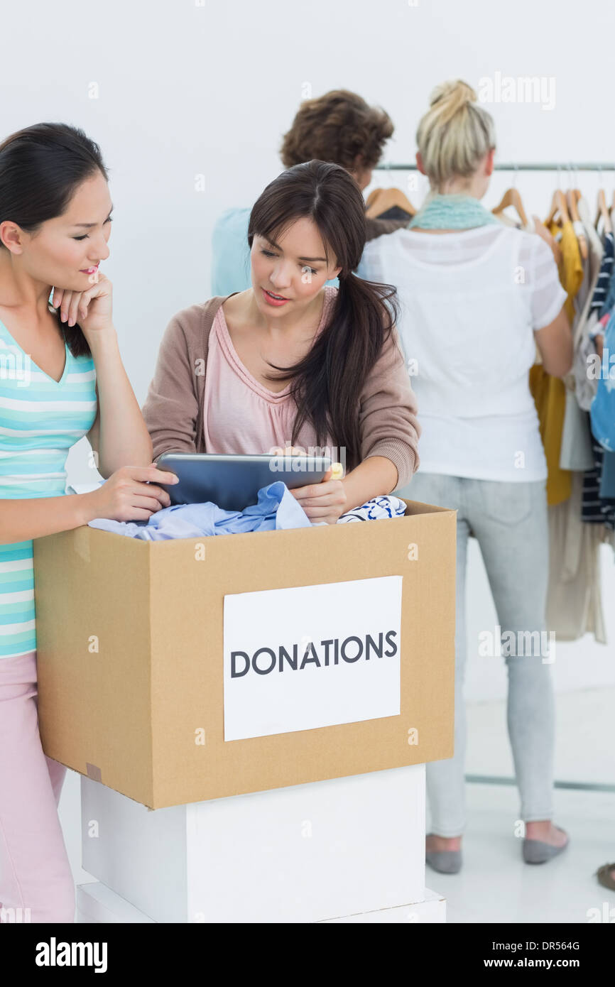 People with clothes donation while using digital tablet Stock Photo