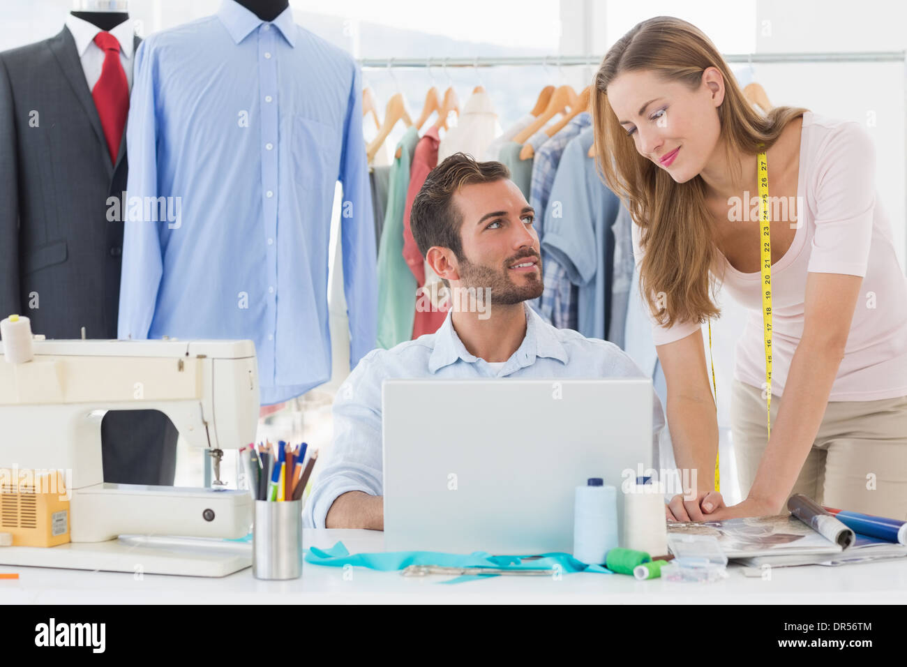Male and female fashion designers using laptop at work in a studio ...