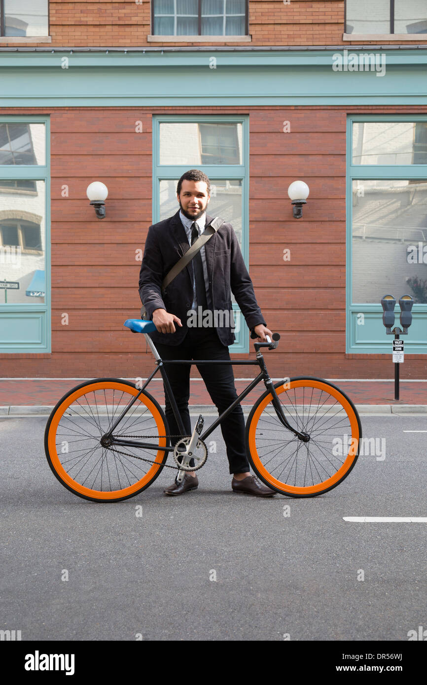 Mixed race businessman with bicycle on city street Stock Photo