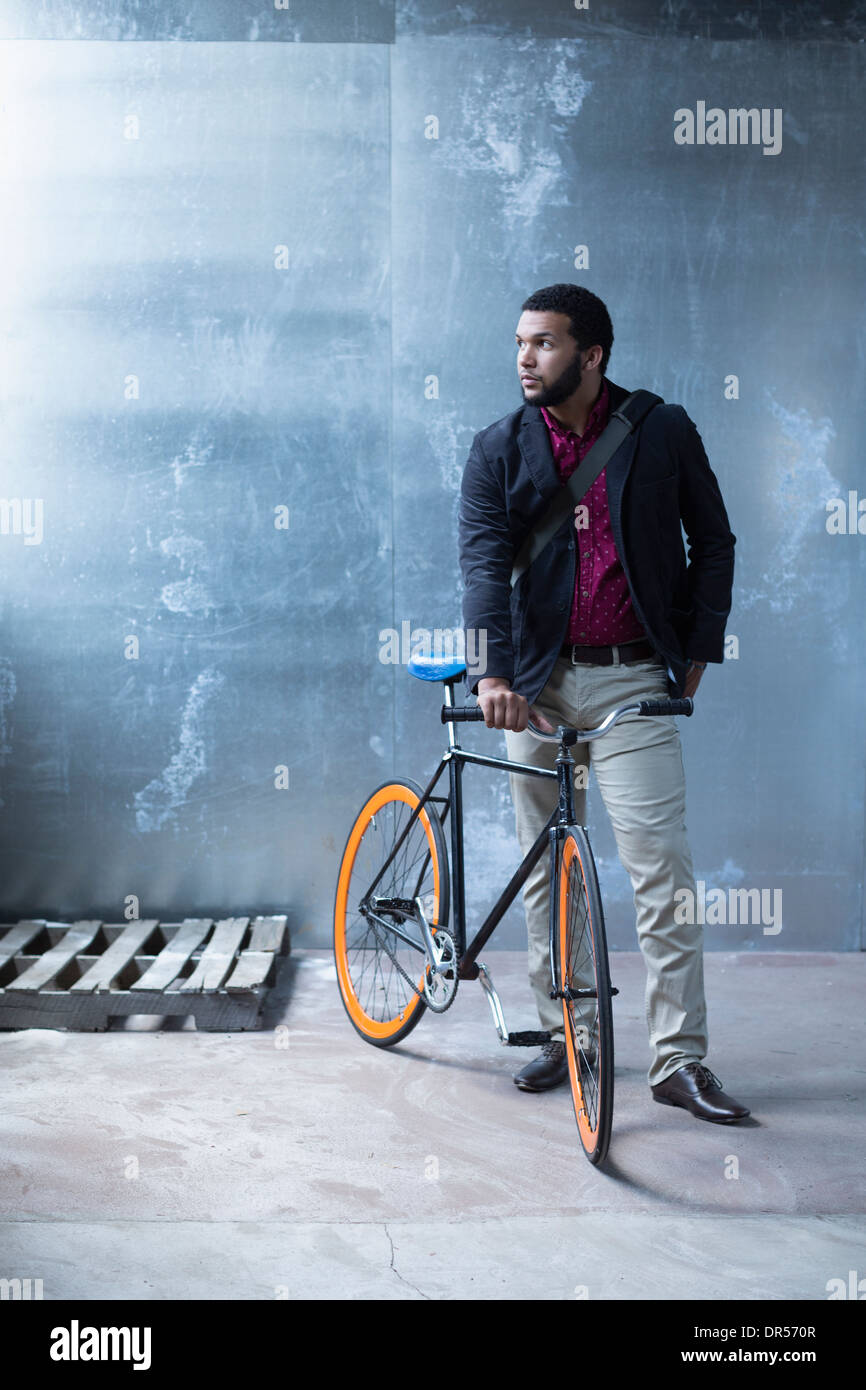 Mixed race businessman with bicycle in warehouse Stock Photo