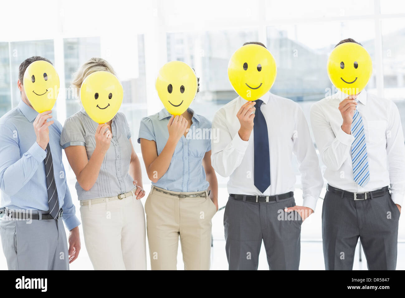 Business people holding happy smiles in front of faces Stock Photo