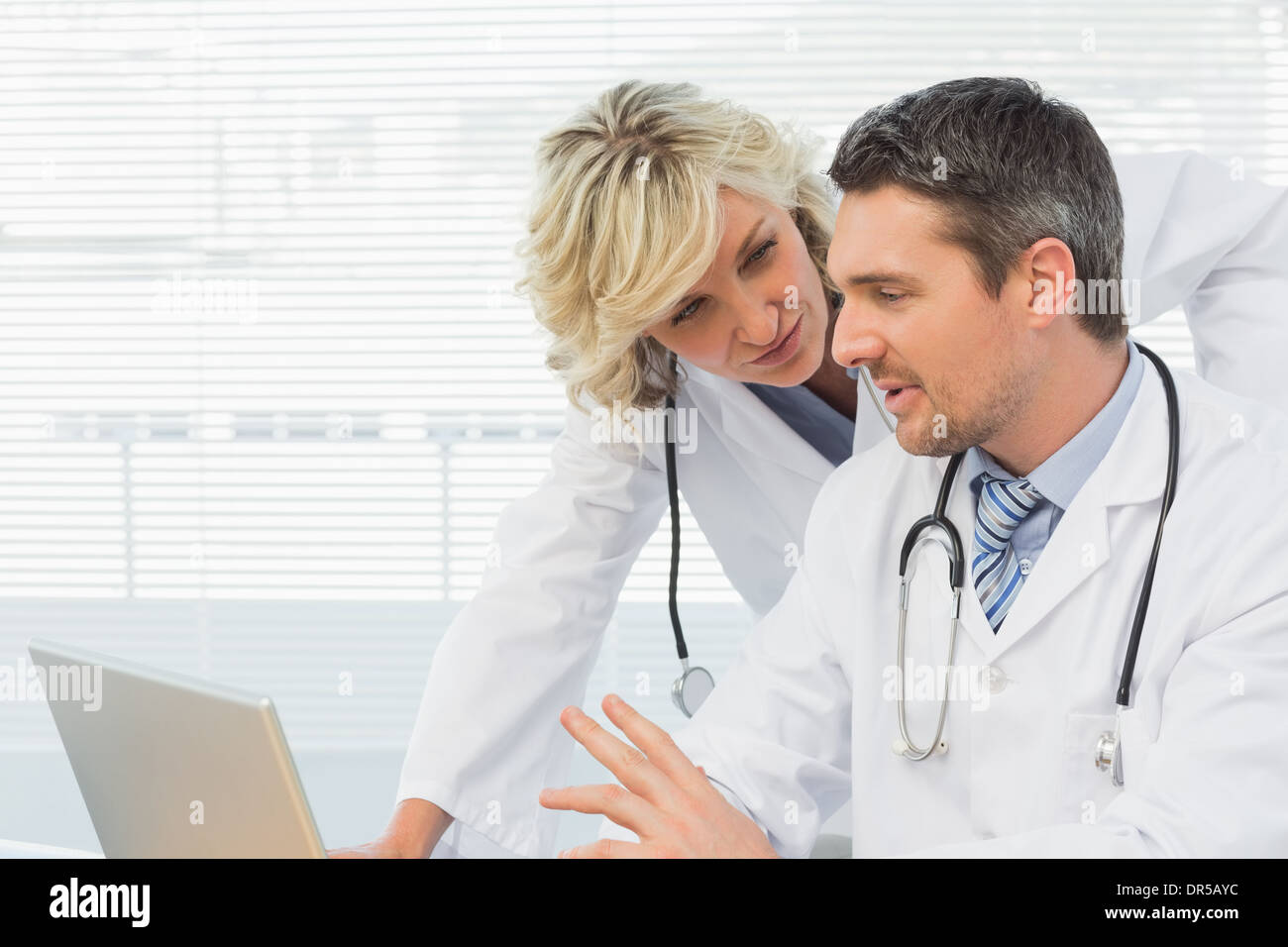 Two concentrated doctors using laptop together Stock Photo