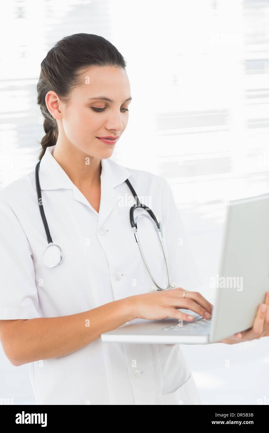 Concentrated young female doctor using laptop Stock Photo
