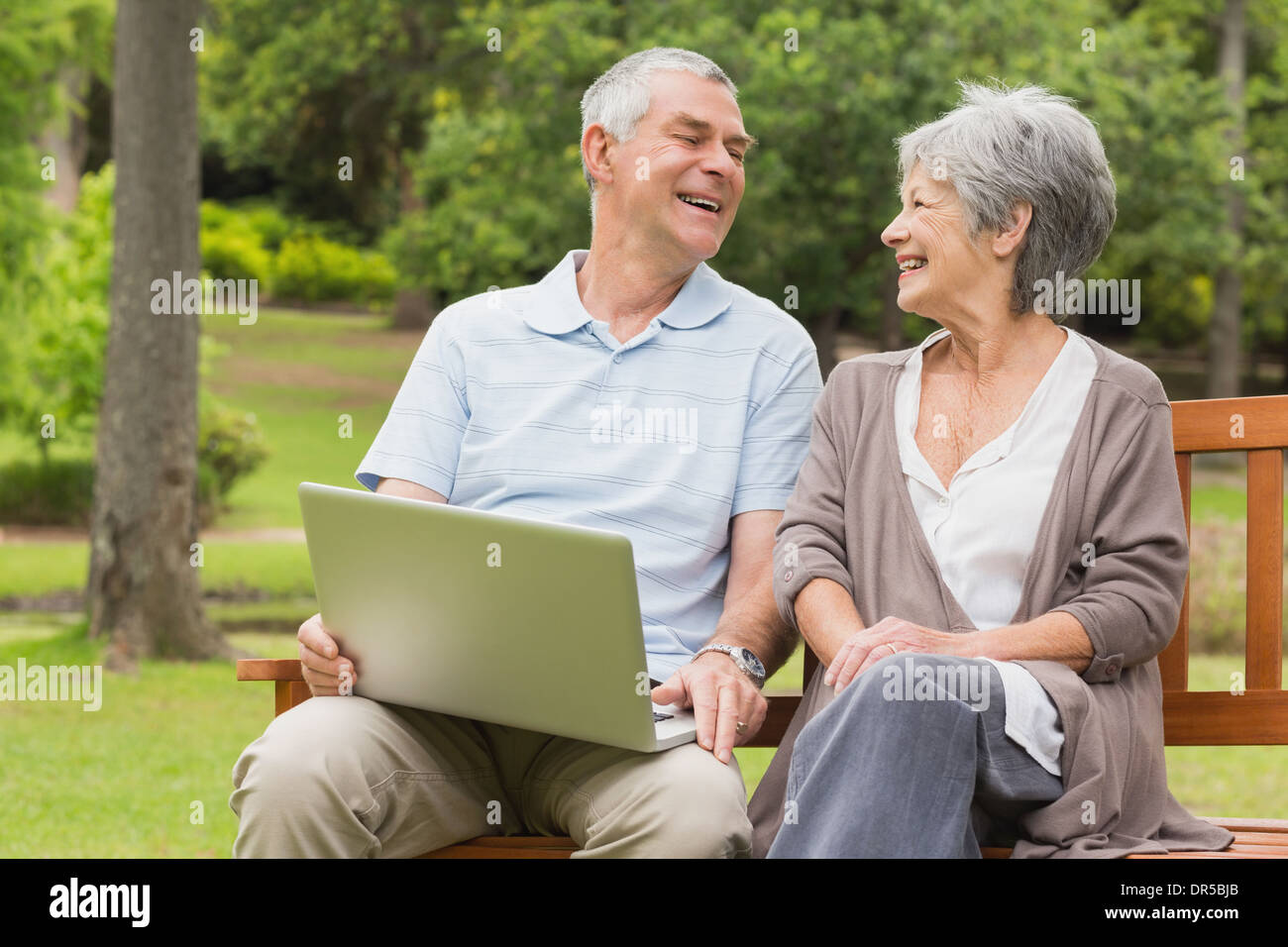 Cheerful senior couple using laptop at park Stock Photo