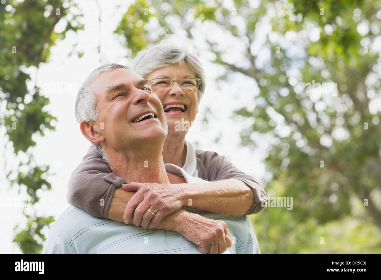 Senior woman embracing man from behind Stock Photo