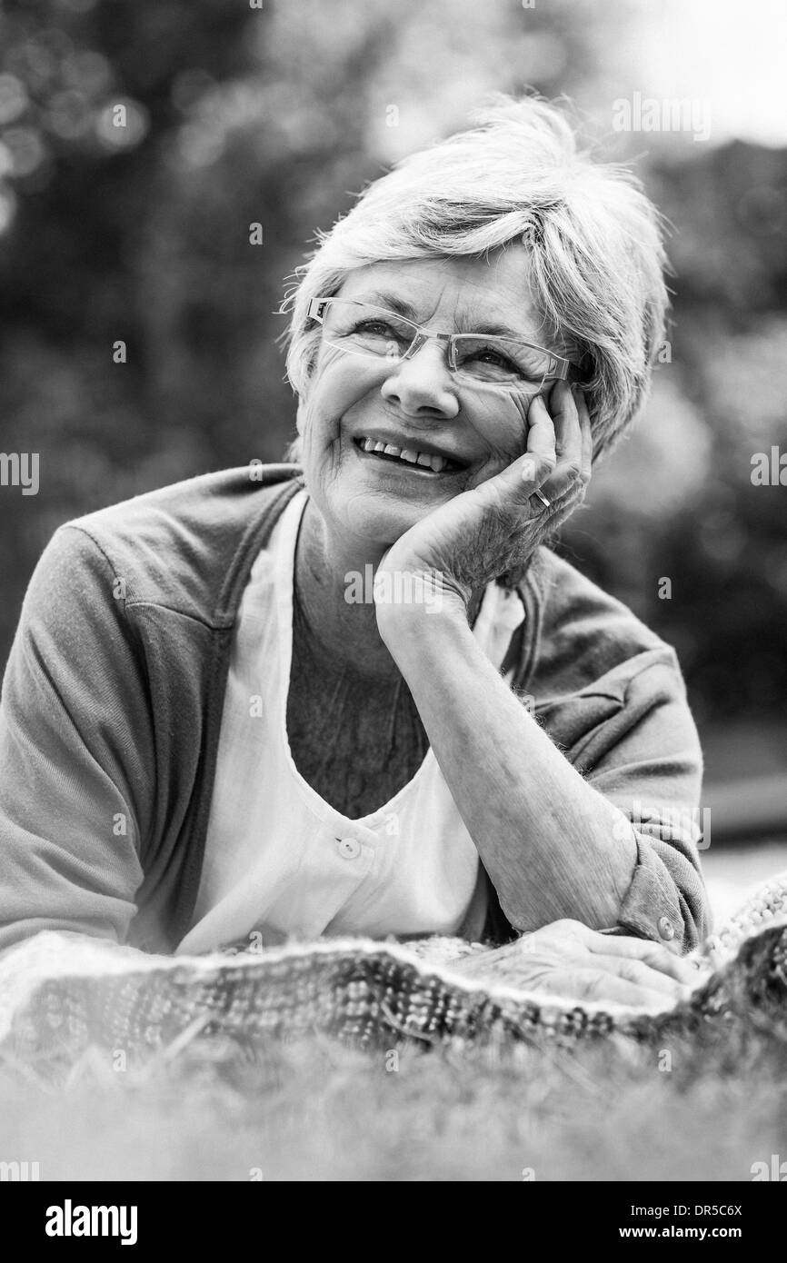 Smiling senior woman lying at park Stock Photo
