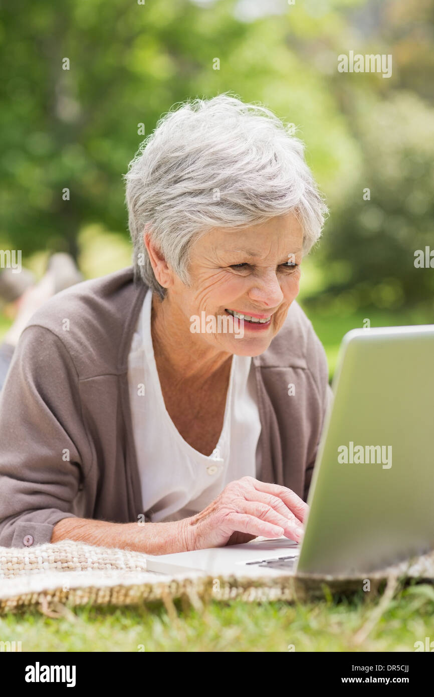 Smiling senior woman using laptop at park Stock Photo