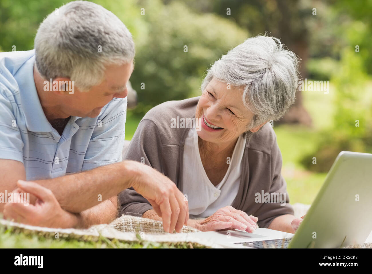 Smiling senior couple using laptop at park Stock Photo