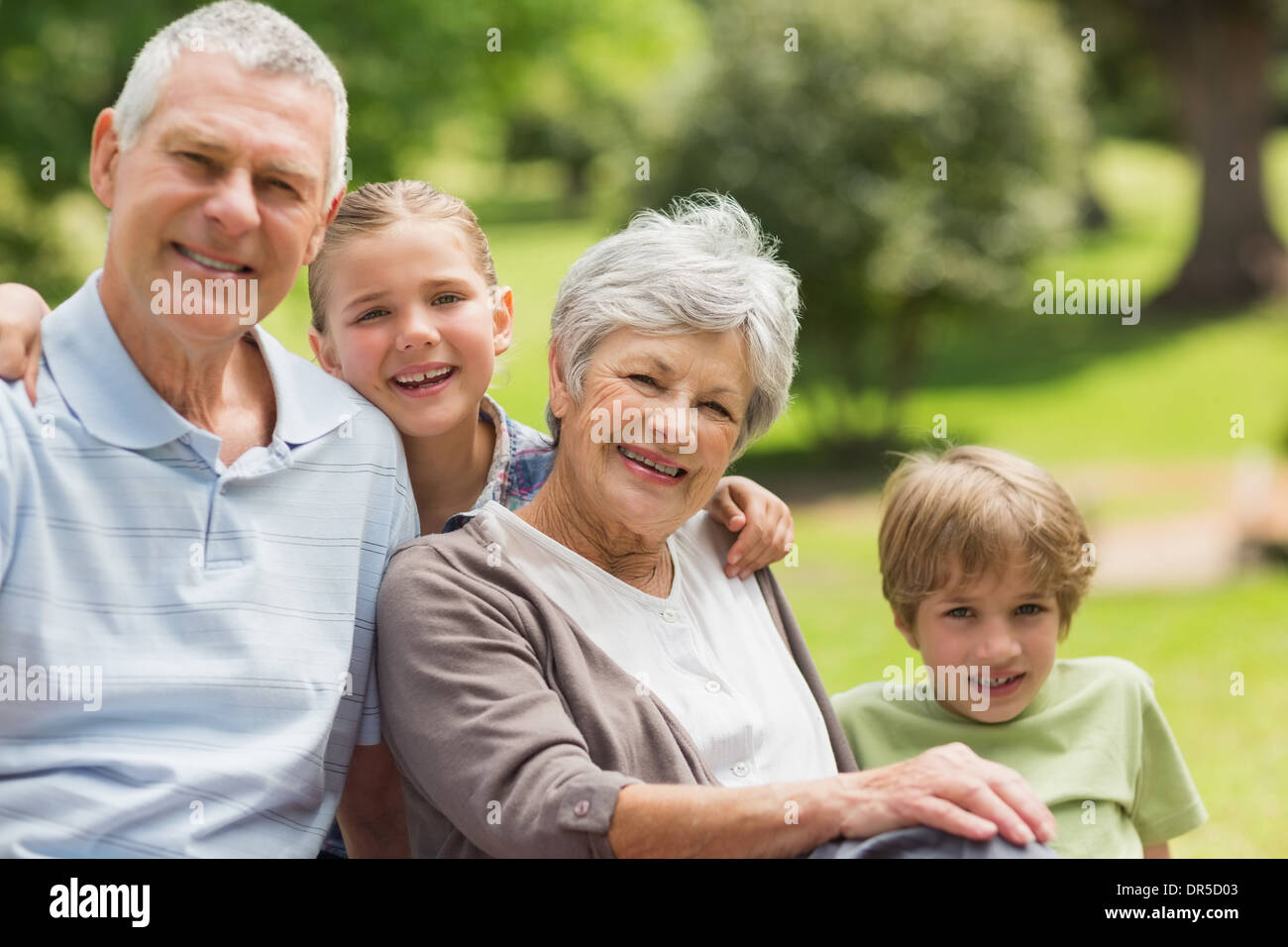 Smiling senior couple and grandchildren at park Stock Photo