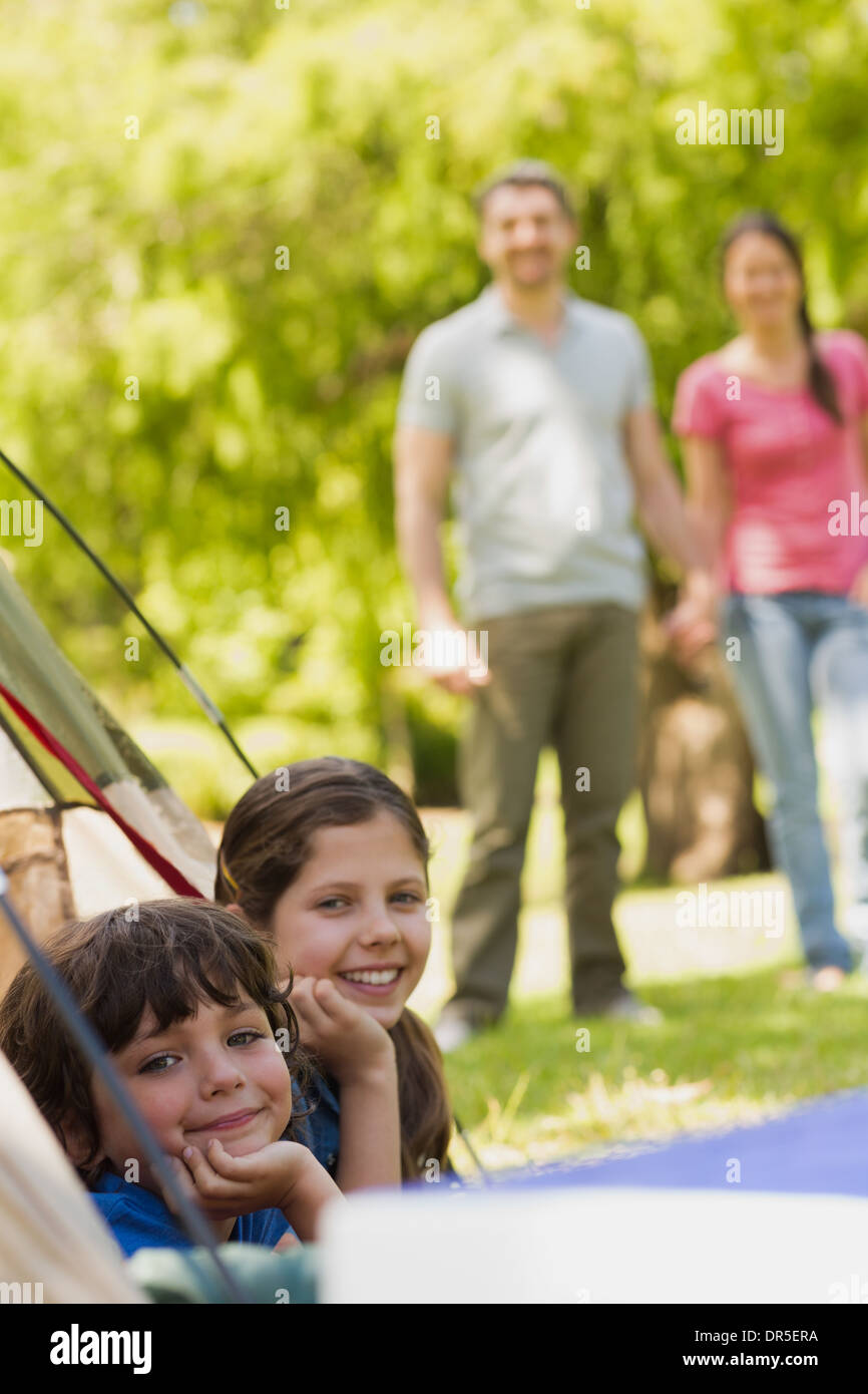 Kids in tent with couple in background at park Stock Photo