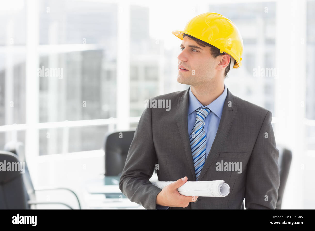Serious architect holding blueprints looking up Stock Photo Alamy