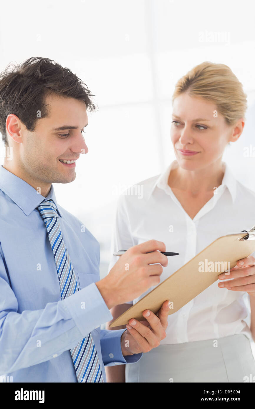 Smiling business team working from clipboard together Stock Photo