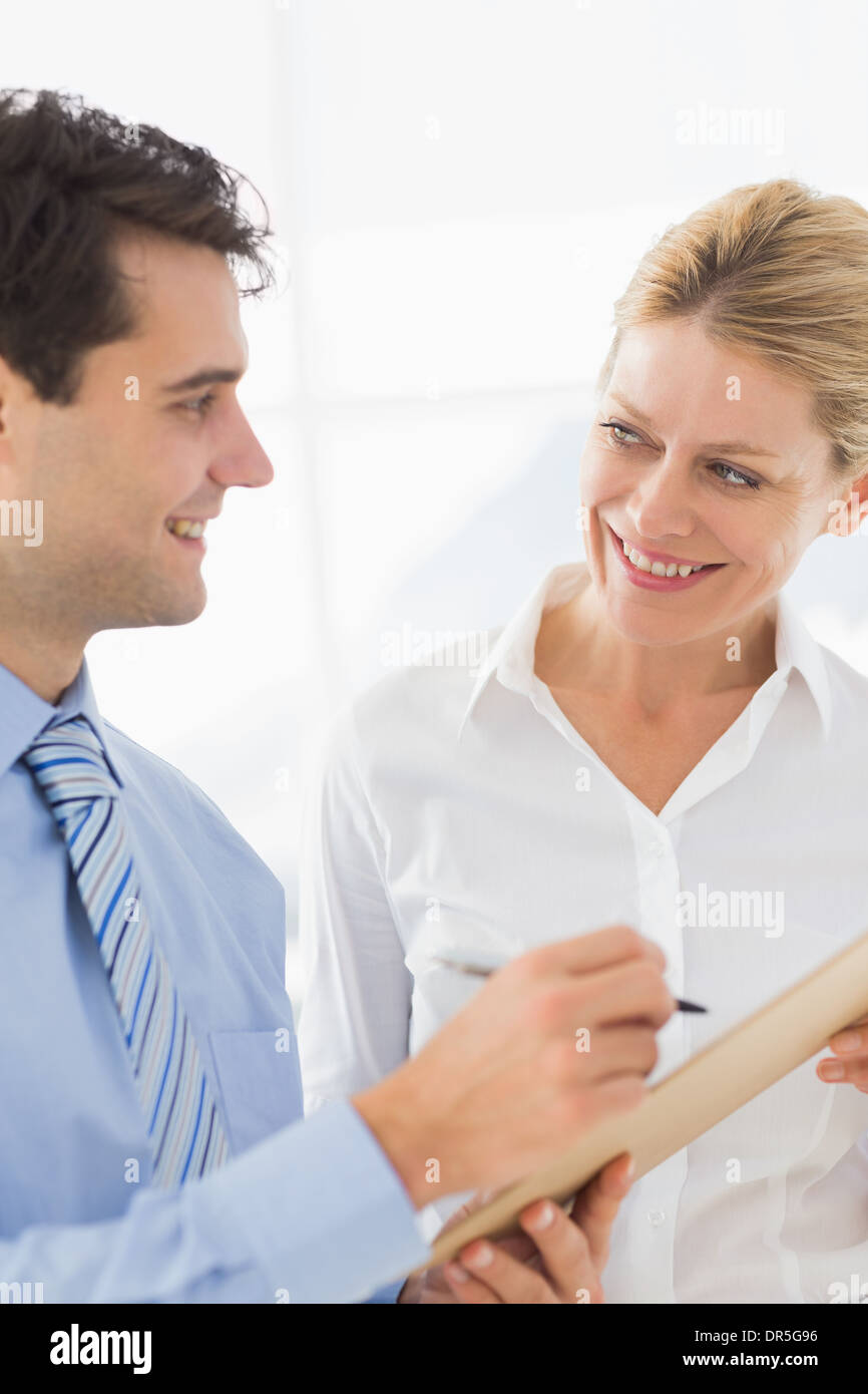 Happy business team working from clipboard together Stock Photo