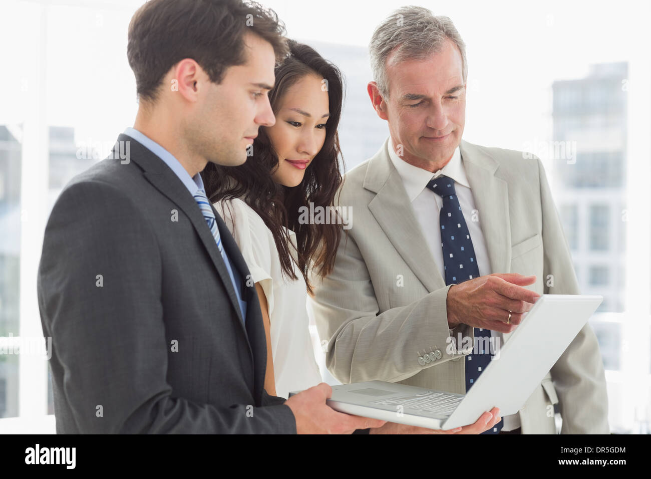 Business team looking at laptop together Stock Photo