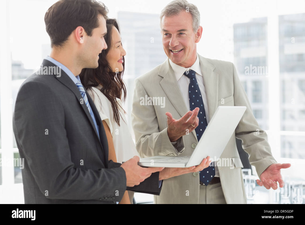 Business team standing and working on laptop together Stock Photo