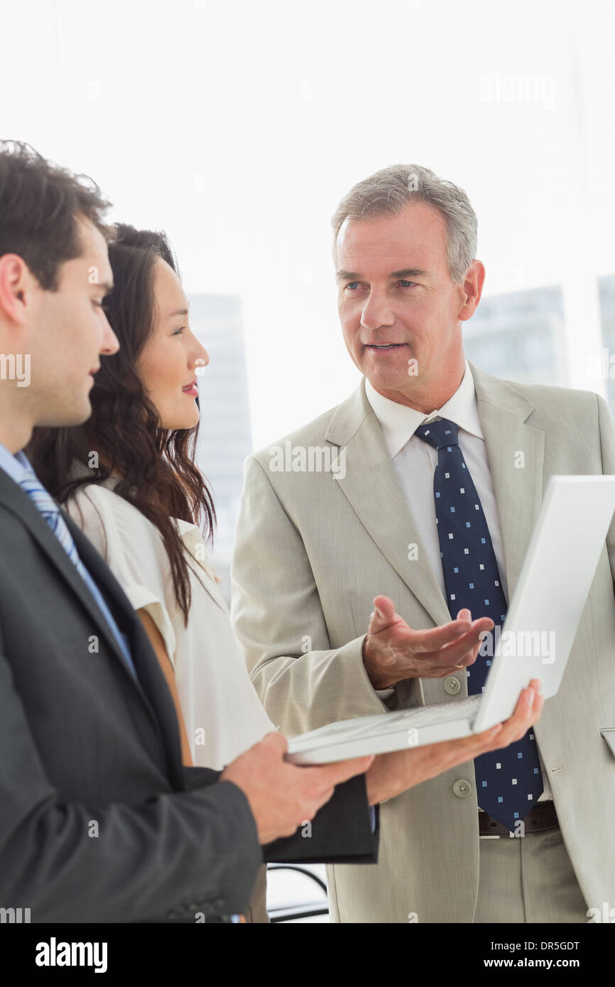 Business team standing and working on laptop together Stock Photo