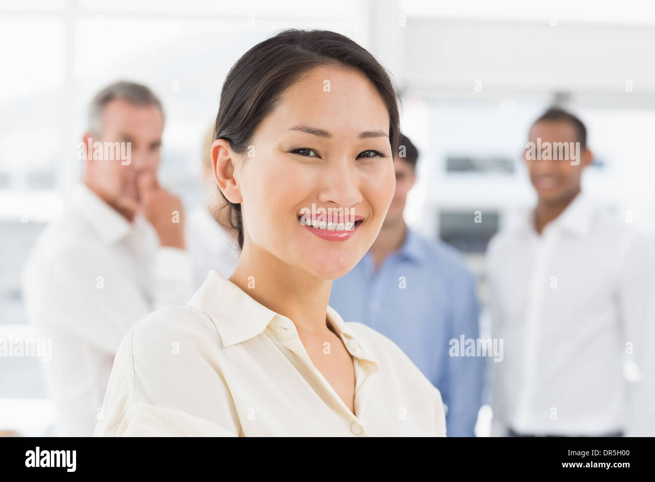Happy asian businesswoman standing with team behind her Stock Photo