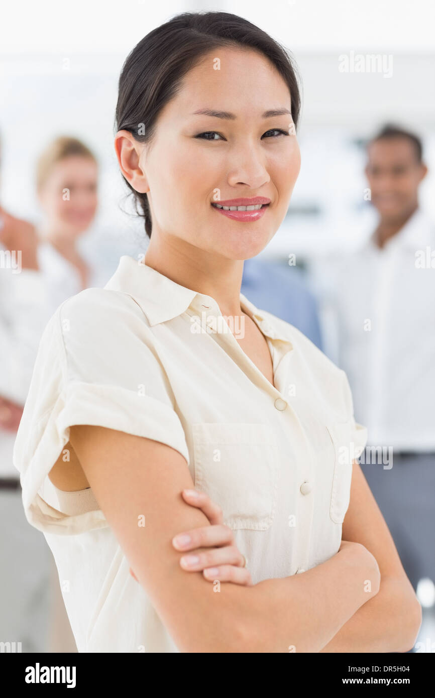 Pretty asian businesswoman standing with team behind her Stock Photo