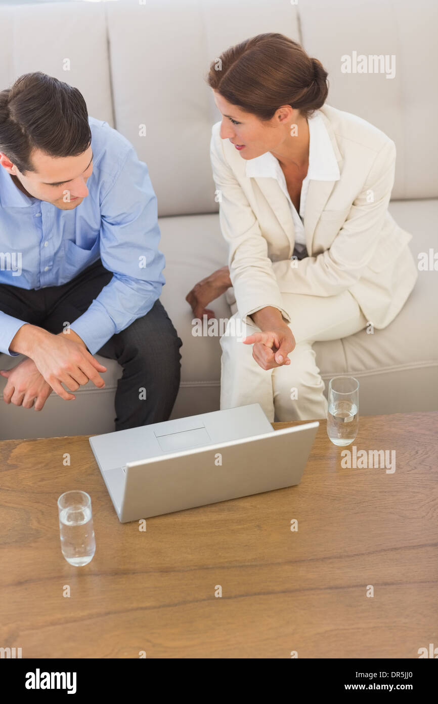 Business partners working on laptop together sitting on sofa Stock Photo