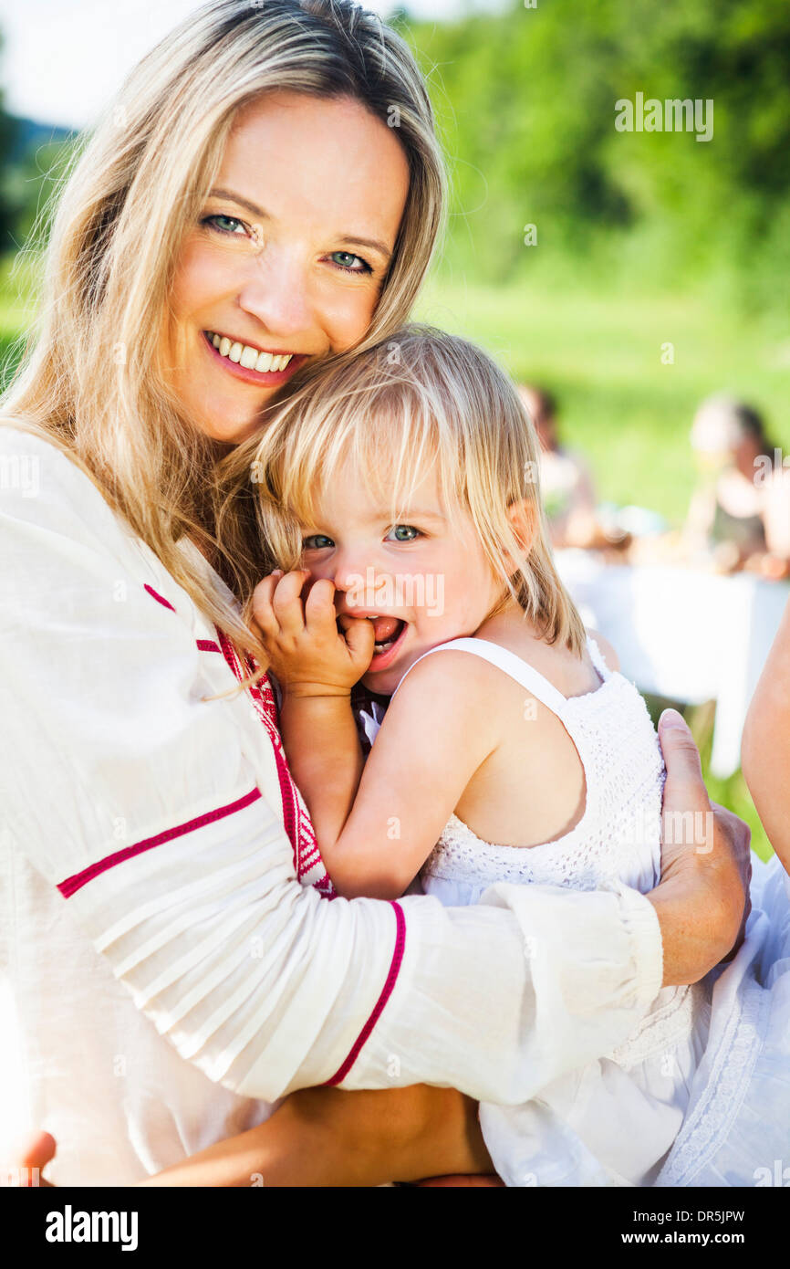 Happy mother with daughter, barbecue in the background, Bavaria, Germany Stock Photo