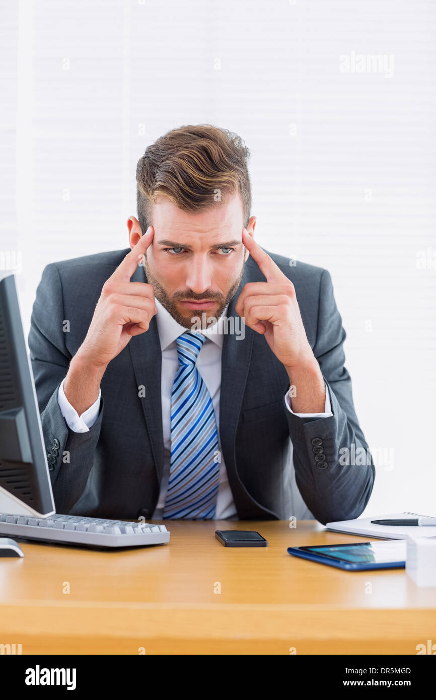 Businessman with severe headache at office desk Stock Photo Alamy