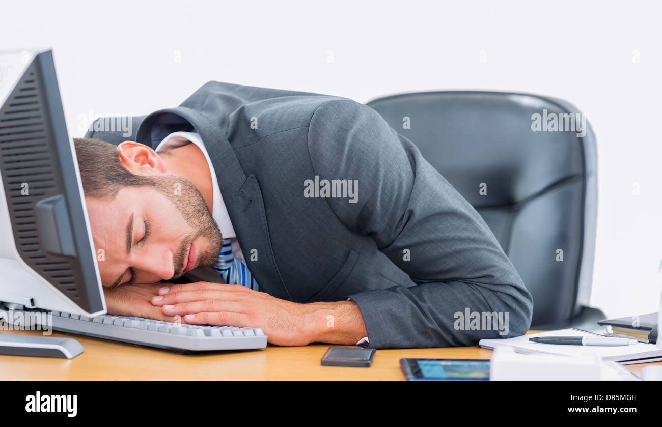 Businessman Resting With Head Over Keyboard At Desk Stock Photo