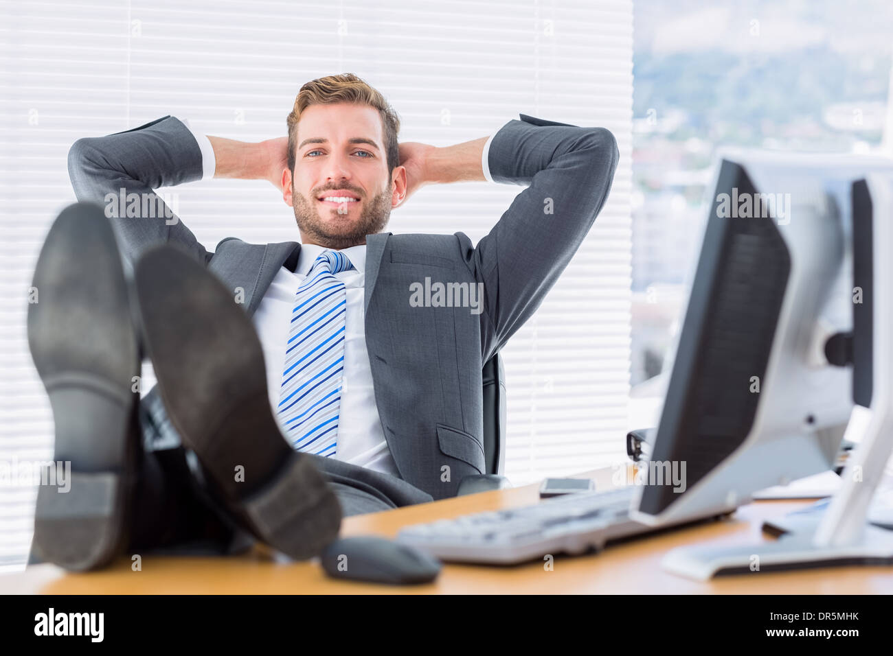 Relaxed businessman sitting with legs on desk Stock Photo - Alamy