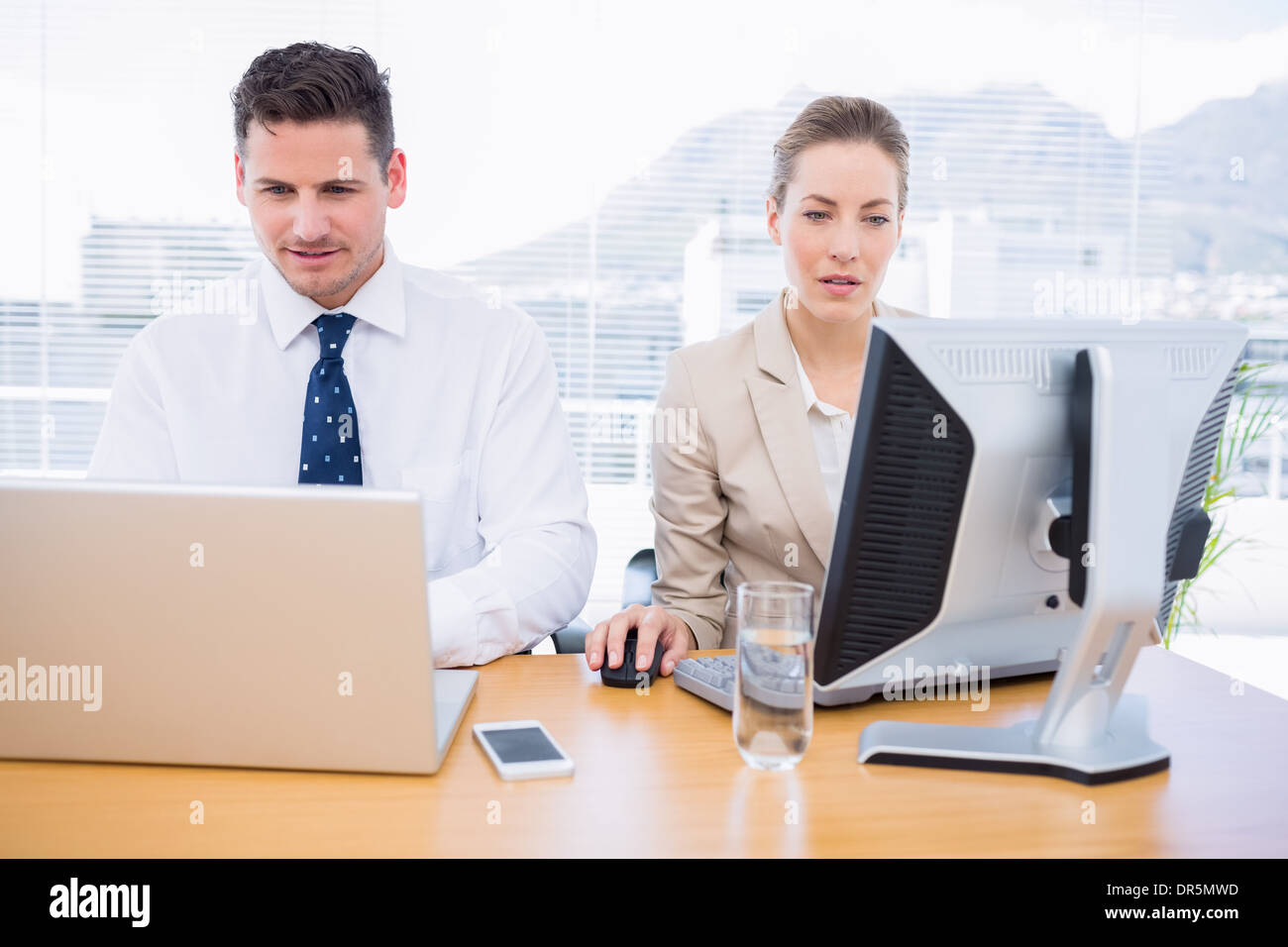 Smartly dressed colleagues using computer and laptop Stock Photo