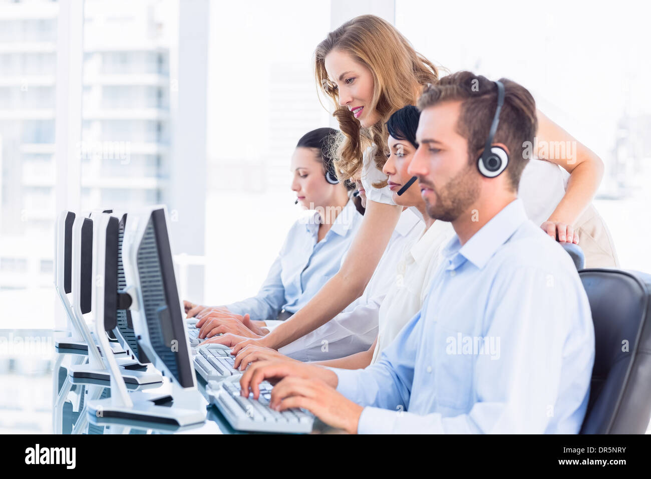 Manager and executives with headsets using computers Stock Photo