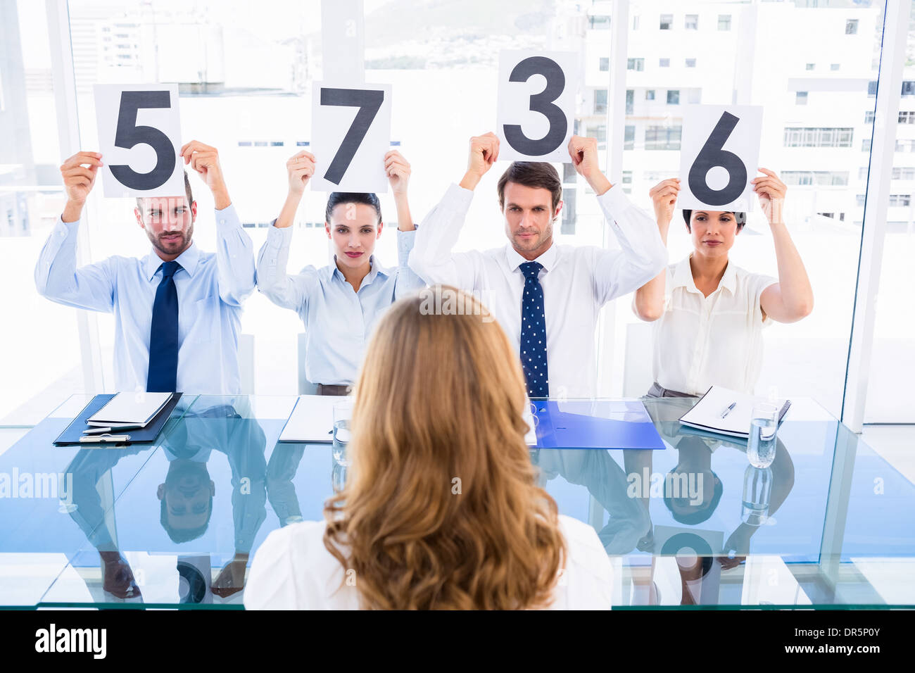 Group of panel judges holding score signs in front of a woman Stock Photo