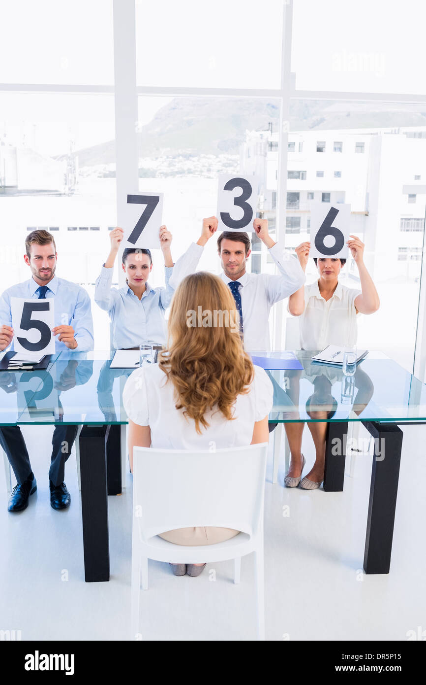 Group of panel judges holding score signs in front of woman Stock Photo