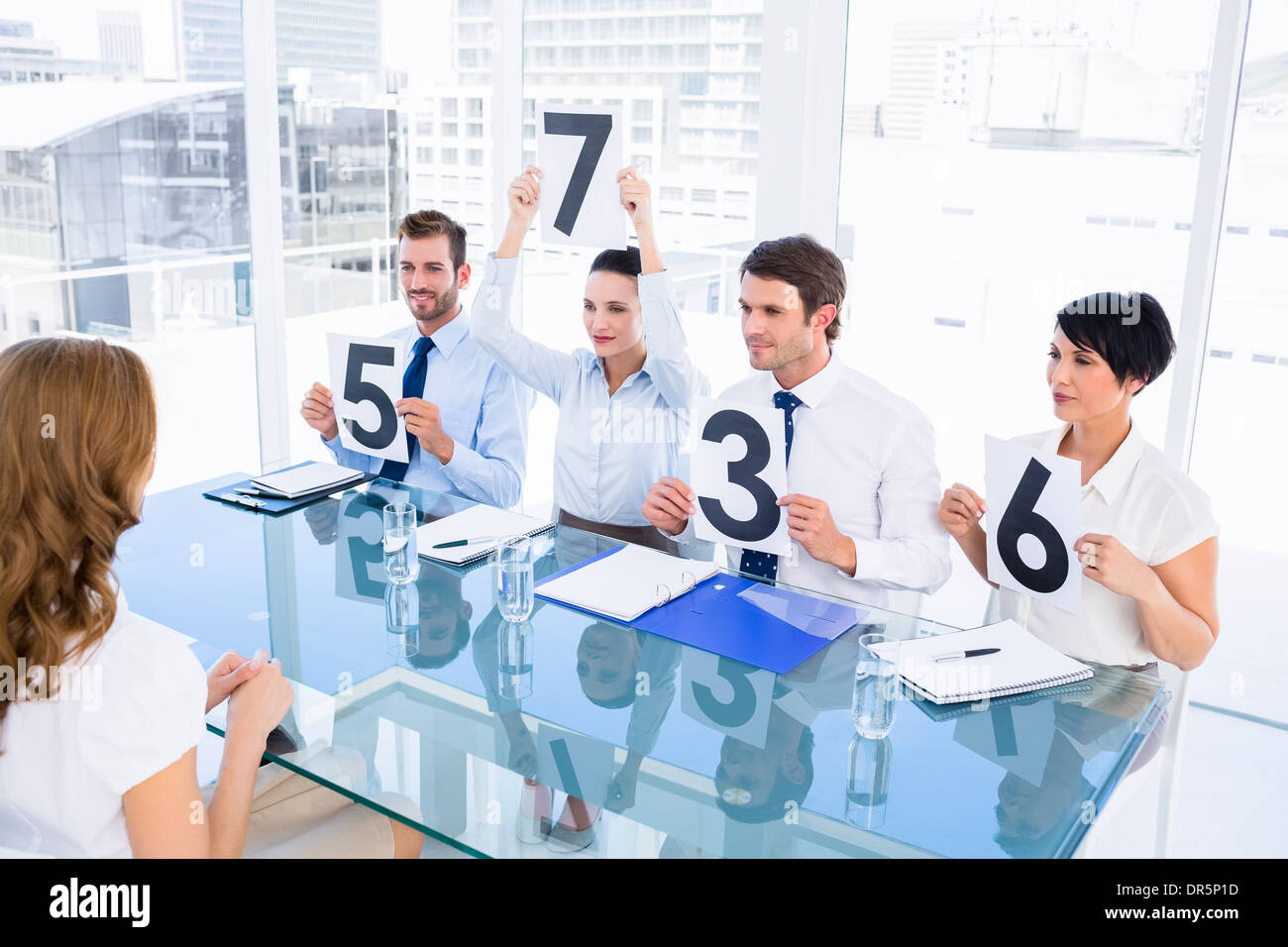 Group of panel judges holding score signs in front of woman Stock Photo