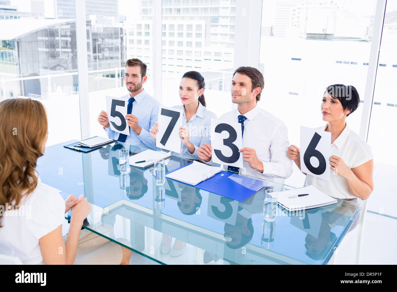 Group of panel judges holding score signs in front of woman Stock Photo