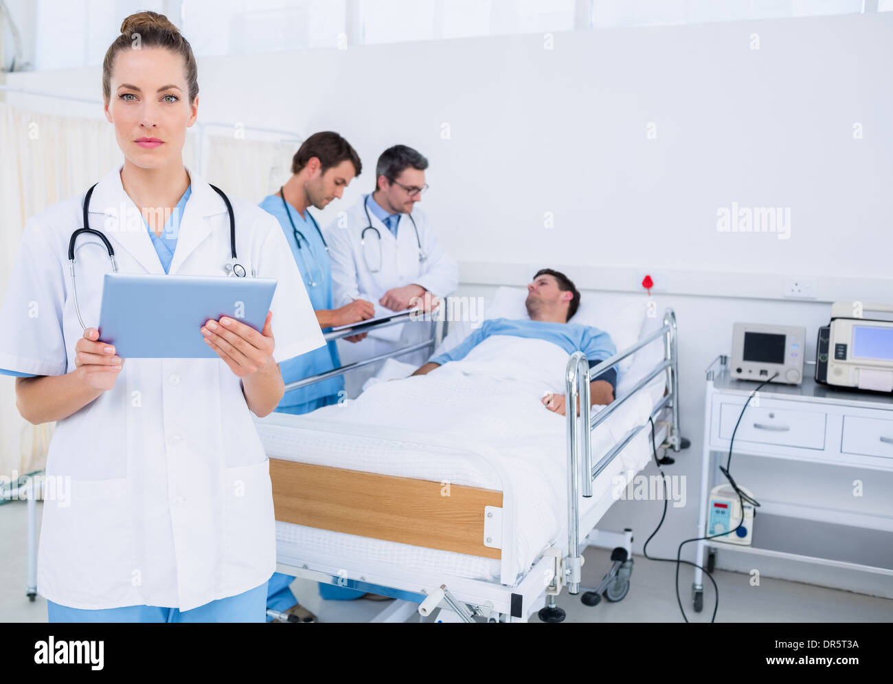 Doctor using digital tablet with colleagues and patient behind Stock ...